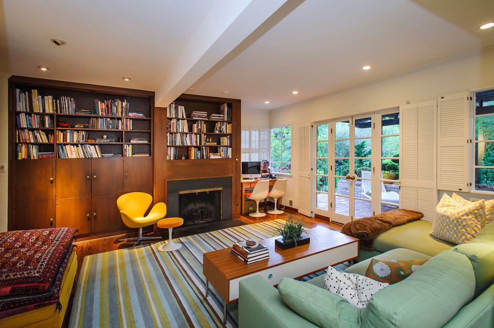 Modelo de sala de estar con biblioteca cerrada actual con suelo de madera en tonos medios y todas las chimeneas