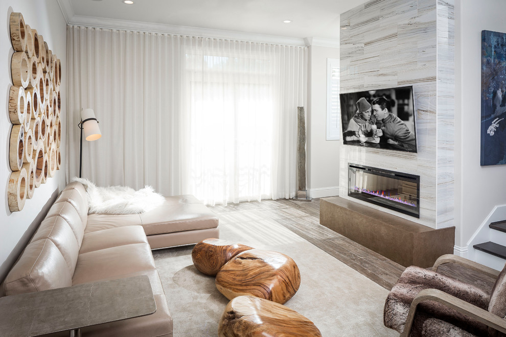 Modelo de sala de estar abierta contemporánea con paredes beige, chimenea lineal y televisor colgado en la pared