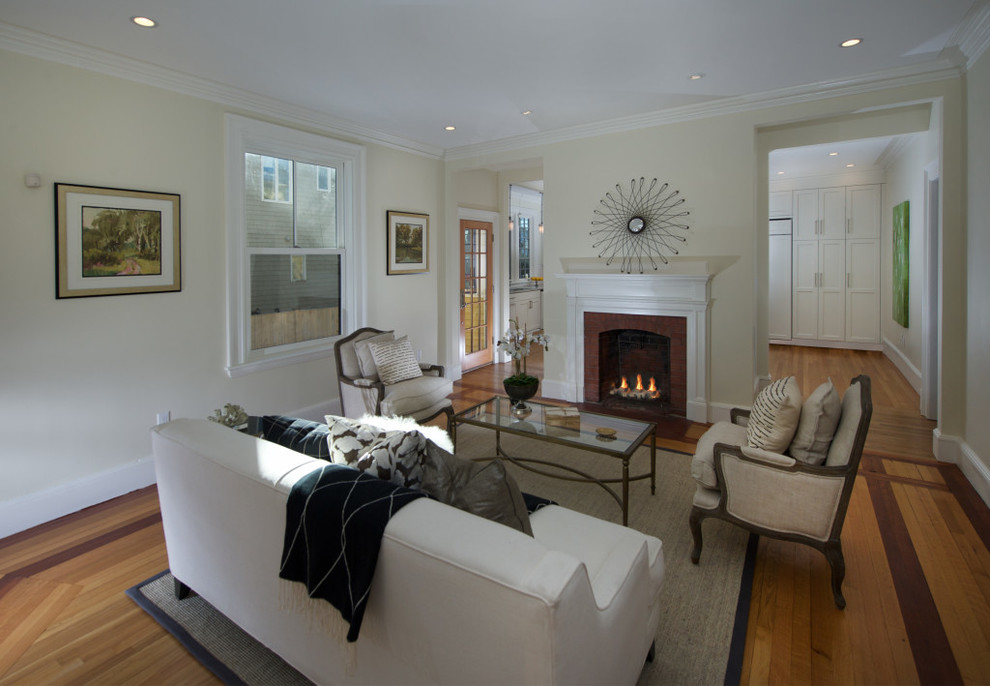 Offenes, Mittelgroßes, Fernseherloses Klassisches Wohnzimmer mit weißer Wandfarbe, braunem Holzboden, Kamin, Kaminumrandung aus Backstein und beigem Boden in Boston
