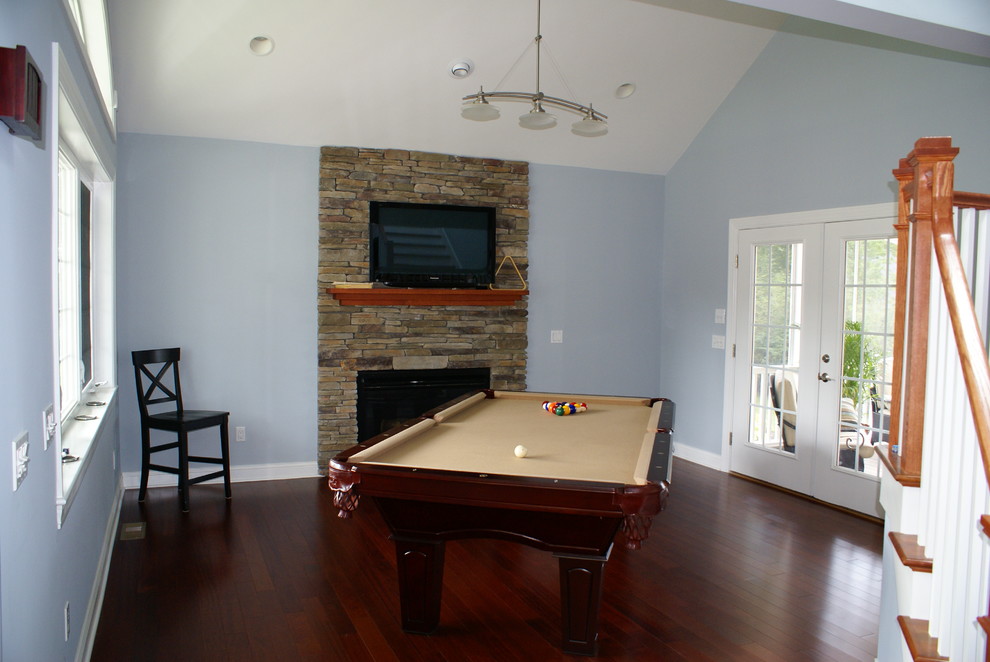 Mittelgroßer Rustikaler Hobbyraum mit blauer Wandfarbe, dunklem Holzboden, Kamin, Kaminumrandung aus Stein und TV-Wand in Providence