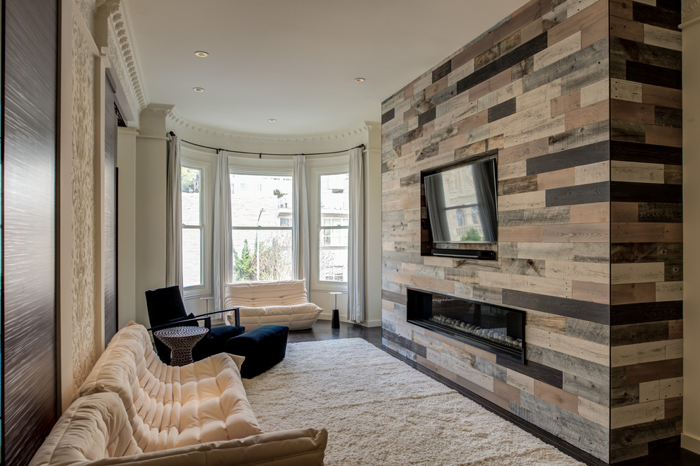 This is an example of a medium sized contemporary enclosed games room in San Francisco with dark hardwood flooring, a ribbon fireplace, white walls, a wooden fireplace surround, a wall mounted tv and brown floors.