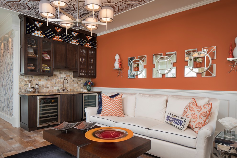 Стильный дизайн: изолированная гостиная комната в стиле фьюжн с домашним баром и оранжевыми стенами - последний тренд