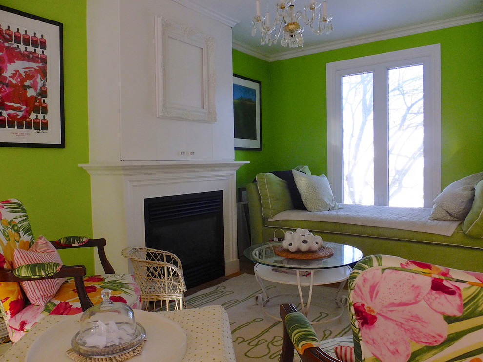 Imagen de sala de estar abierta clásica renovada pequeña con paredes verdes, suelo de madera clara, todas las chimeneas, marco de chimenea de hormigón y televisor retractable