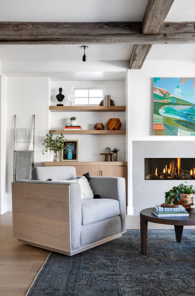 Imagen de sala de estar abierta marinera grande sin televisor con paredes blancas, suelo de madera clara, chimenea lineal, marco de chimenea de piedra y suelo beige
