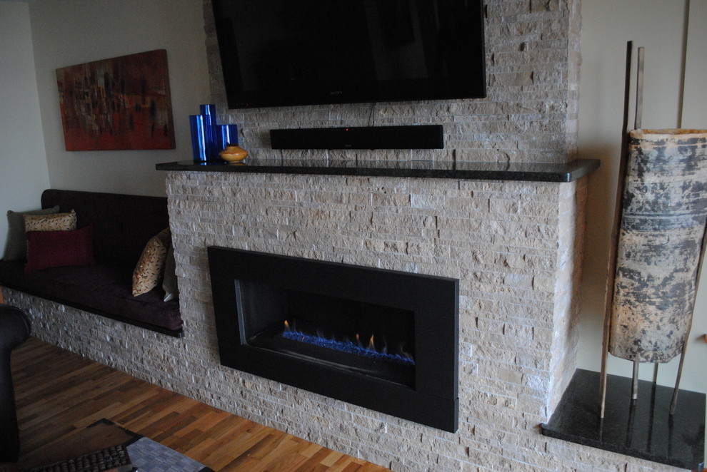 バンクーバーにある広いトランジショナルスタイルのおしゃれなオープンリビング (ベージュの壁、淡色無垢フローリング、横長型暖炉、石材の暖炉まわり、壁掛け型テレビ) の写真