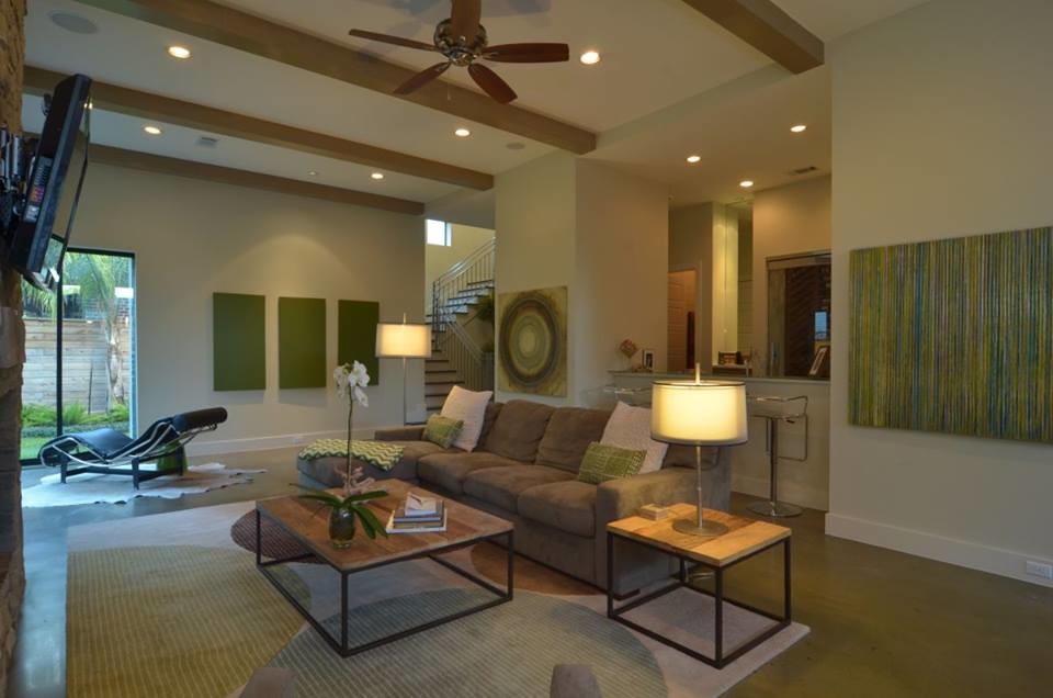 Large transitional open concept concrete floor family room photo in Houston with beige walls, a standard fireplace, a stone fireplace and a wall-mounted tv