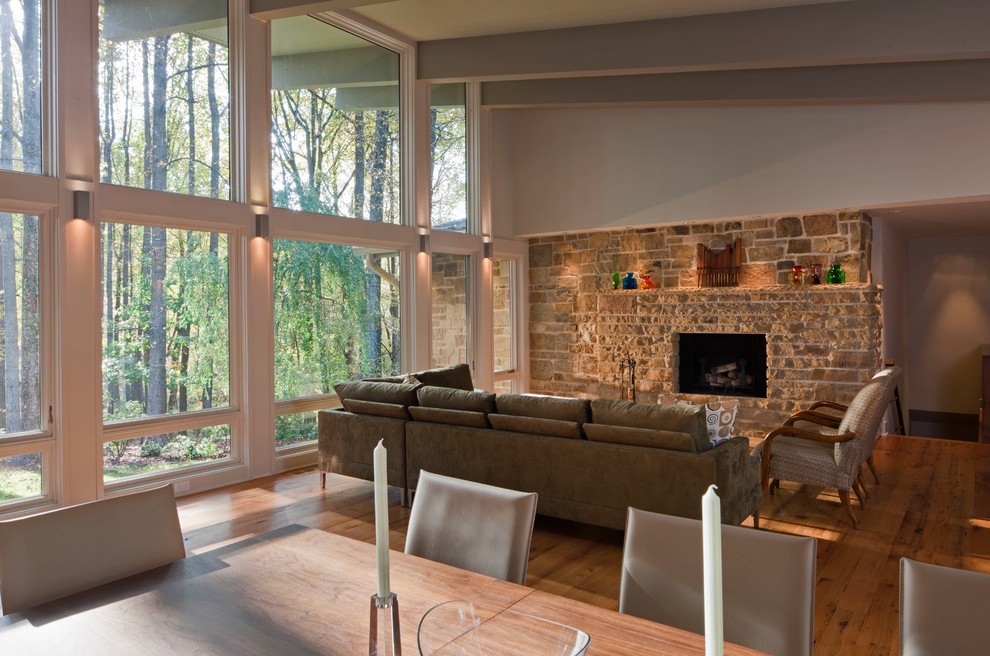 This is an example of a large contemporary open plan games room in Baltimore with medium hardwood flooring, a standard fireplace, a stone fireplace surround, no tv, a music area, grey walls and brown floors.