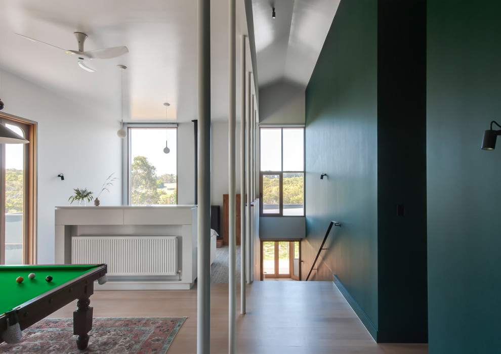 Immagine di un grande soggiorno minimalista chiuso con sala giochi, pareti verdi, pavimento in legno verniciato, stufa a legna, TV autoportante e pavimento bianco