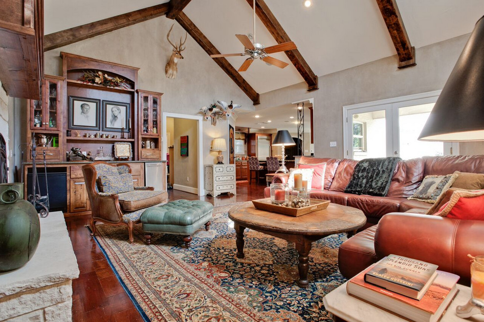 Foto de sala de estar abierta de estilo americano grande con paredes beige, suelo de madera en tonos medios, todas las chimeneas, marco de chimenea de piedra y pared multimedia