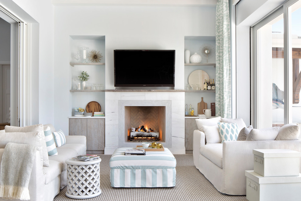 На фото: изолированная гостиная комната в морском стиле с белыми стенами, стандартным камином, телевизором на стене и ковром на полу с