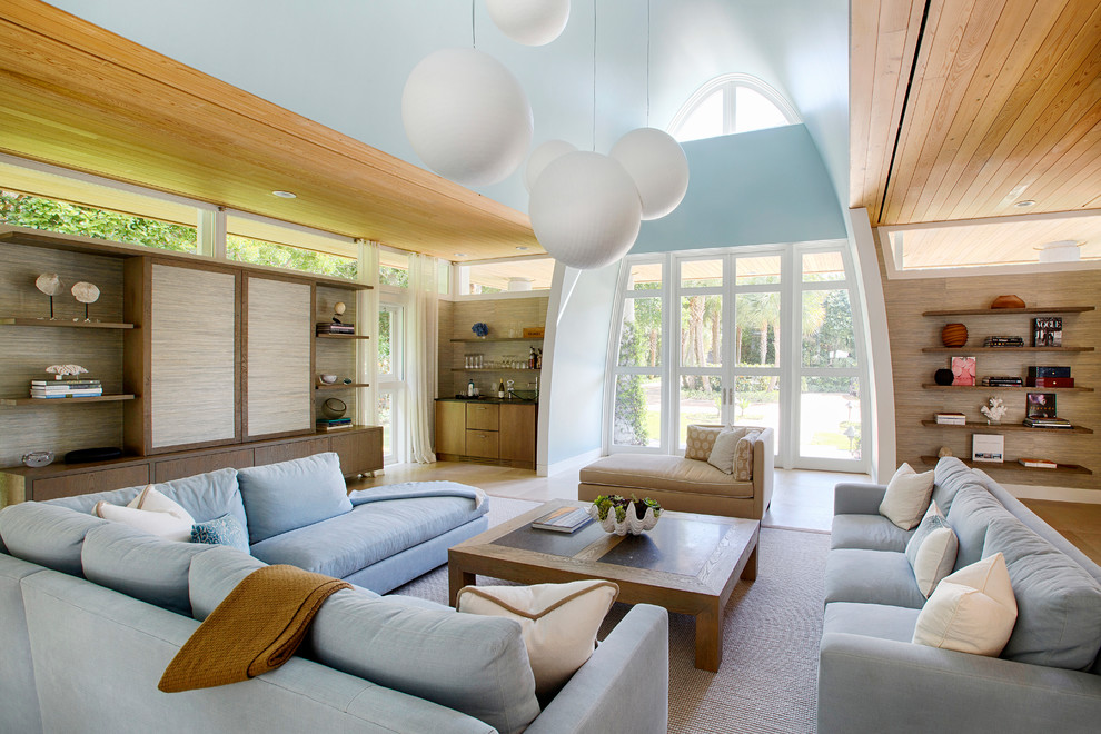 Großes, Offenes Modernes Wohnzimmer ohne Kamin mit verstecktem TV, blauer Wandfarbe, braunem Boden und Laminat in Miami