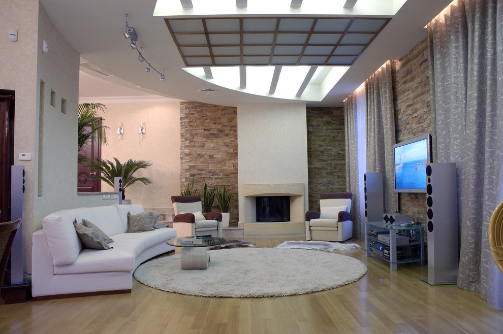 This is an example of a contemporary games room in Other with beige walls, light hardwood flooring, a standard fireplace and a wall mounted tv.