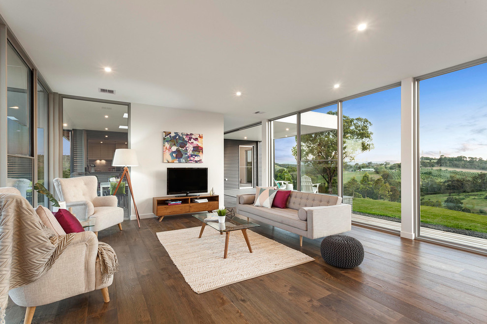 Modernes Wohnzimmer ohne Kamin mit weißer Wandfarbe, dunklem Holzboden und freistehendem TV in Melbourne