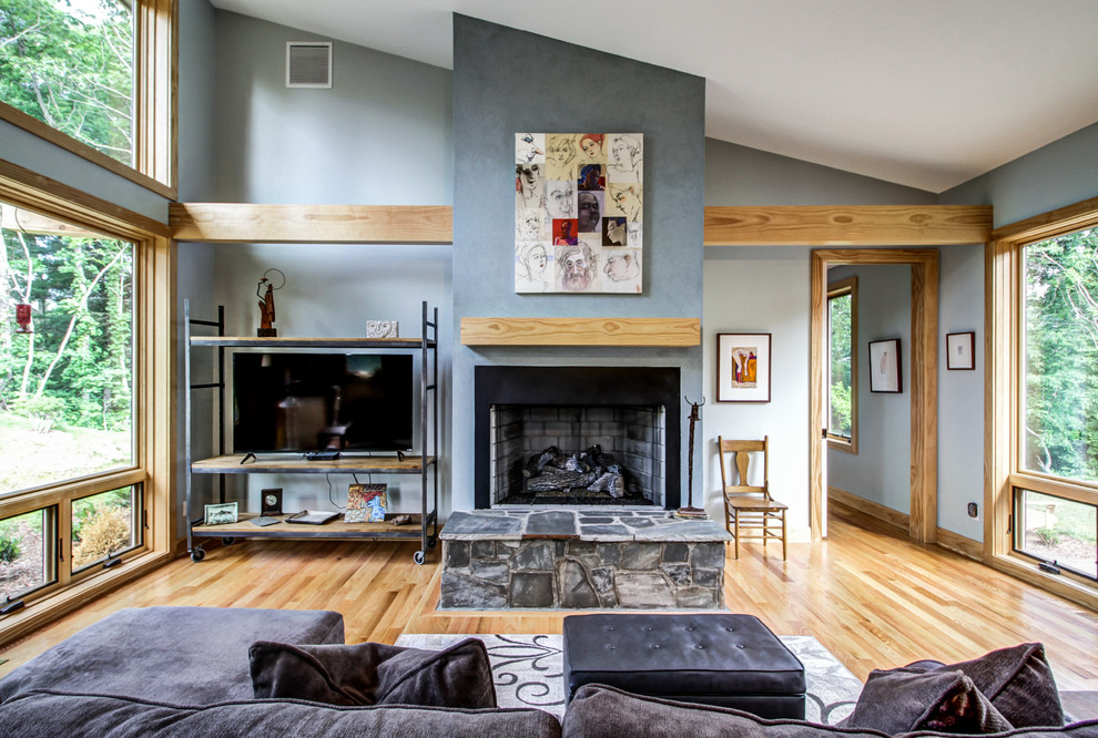 Diseño de sala de estar abierta clásica renovada de tamaño medio con paredes grises, suelo de madera clara, todas las chimeneas, marco de chimenea de hormigón y televisor independiente