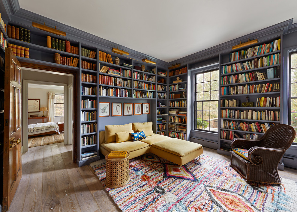 Пример оригинального дизайна: гостиная комната в стиле фьюжн с с книжными шкафами и полками, фиолетовыми стенами, паркетным полом среднего тона и коричневым полом