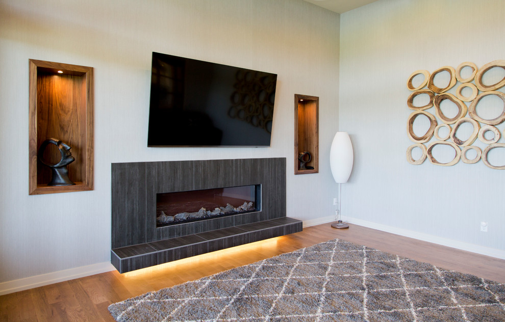 Mid-sized trendy enclosed medium tone wood floor and brown floor family room photo in Kansas City with beige walls, a ribbon fireplace, a tile fireplace and a wall-mounted tv