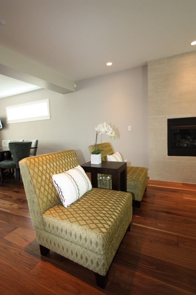 Mittelgroßes, Offenes Klassisches Wohnzimmer mit grauer Wandfarbe, braunem Holzboden, Kamin, gefliester Kaminumrandung und freistehendem TV in Vancouver