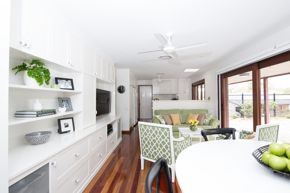 Diseño de sala de estar tradicional pequeña sin chimenea con paredes blancas, suelo de madera en tonos medios y pared multimedia