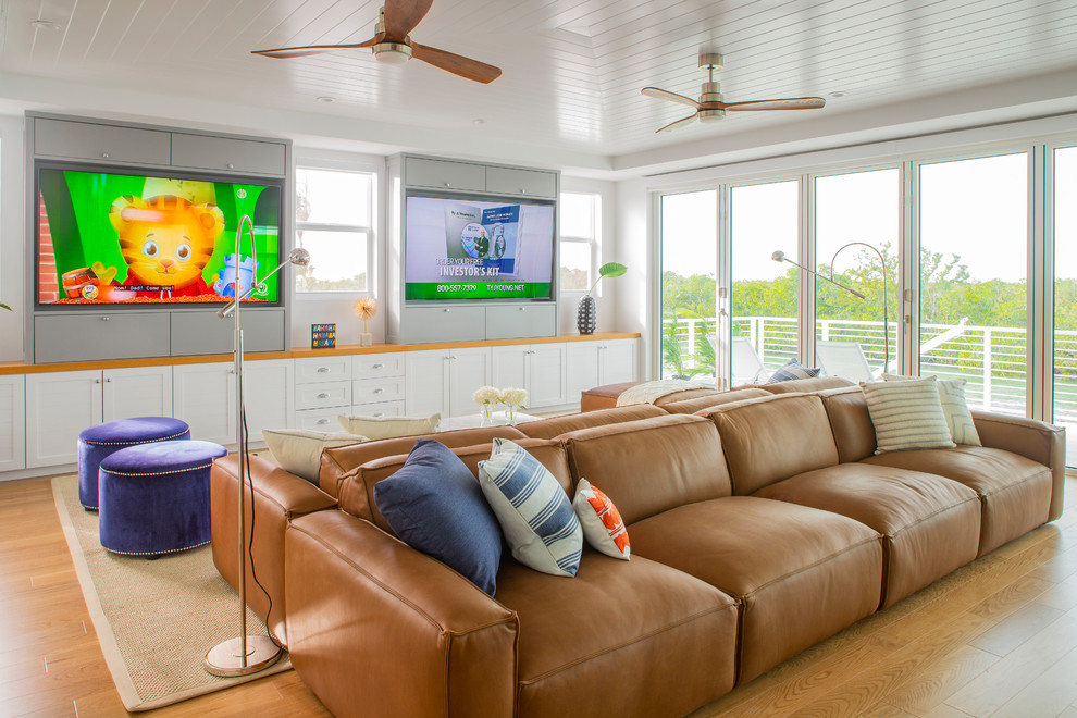 Ejemplo de sala de estar abierta costera de tamaño medio con pared multimedia, paredes blancas, suelo de madera en tonos medios, suelo marrón y alfombra