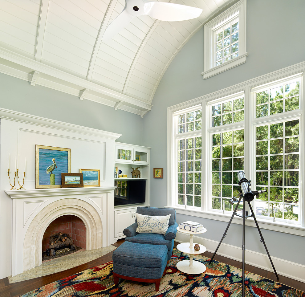 На фото: гостиная комната в стиле неоклассика (современная классика) с синими стенами, темным паркетным полом, стандартным камином и телевизором на стене с