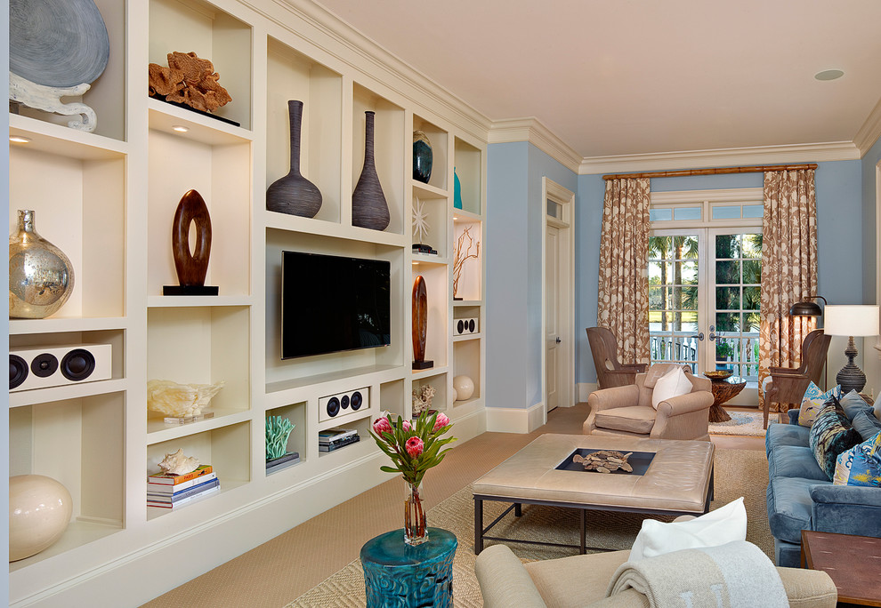 На фото: большая изолированная гостиная комната в морском стиле с телевизором на стене, синими стенами, ковровым покрытием, бежевым полом и синим диваном с