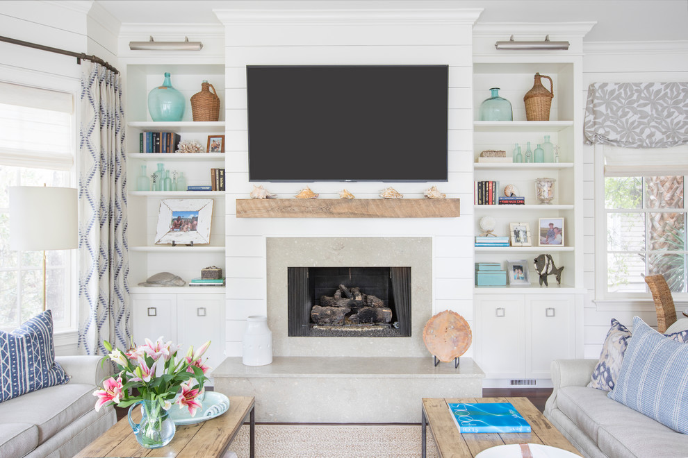 Maritimes Wohnzimmer mit weißer Wandfarbe, dunklem Holzboden, Kamin, Kaminumrandung aus Stein, TV-Wand und braunem Boden in Charleston
