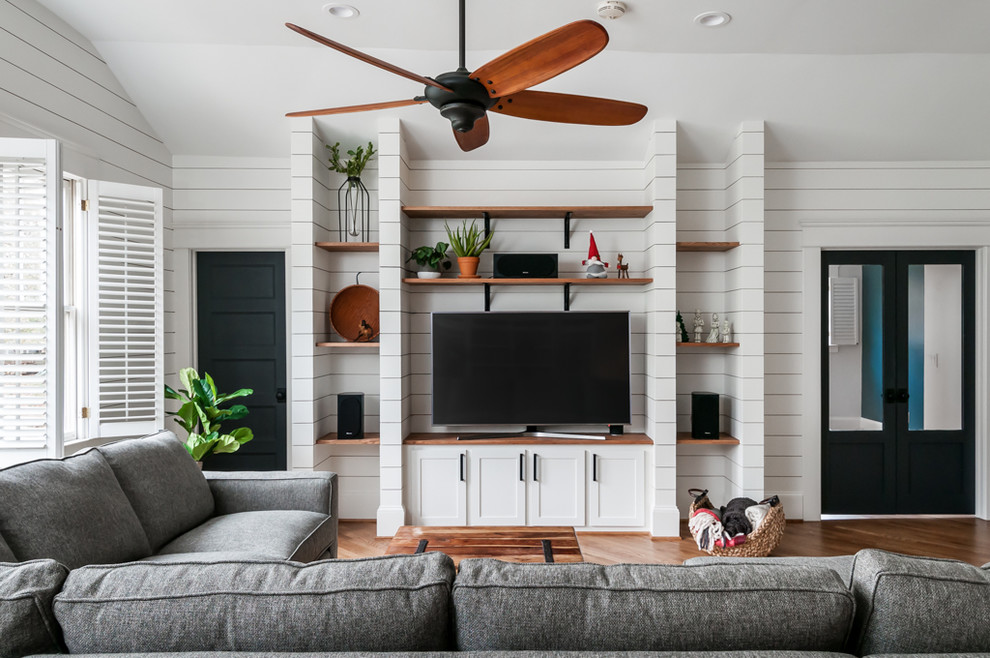 Foto de sala de estar clásica renovada sin chimenea con paredes blancas, suelo de madera en tonos medios y pared multimedia