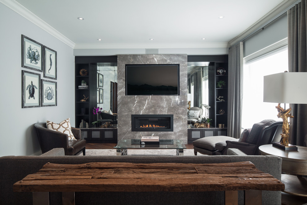 This is an example of a medium sized contemporary open plan games room in Toronto with grey walls, medium hardwood flooring, a standard fireplace, a stone fireplace surround and a wall mounted tv.
