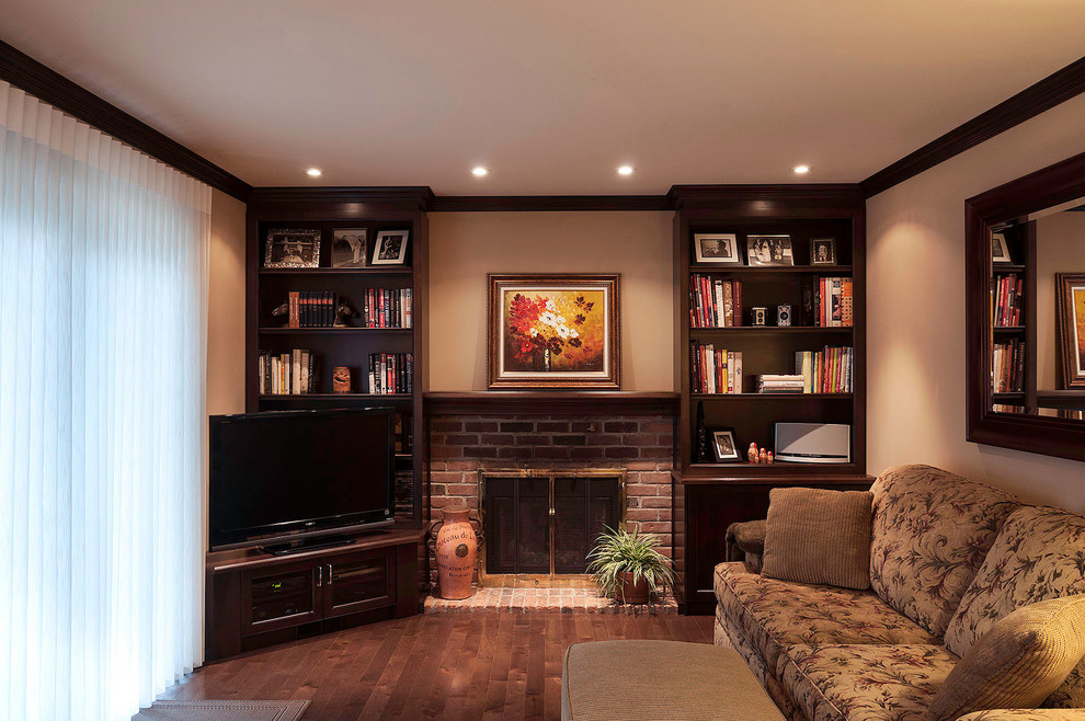 Photo of a small traditional enclosed games room in Montreal with beige walls, medium hardwood flooring, a standard fireplace, a brick fireplace surround, a freestanding tv and brown floors.