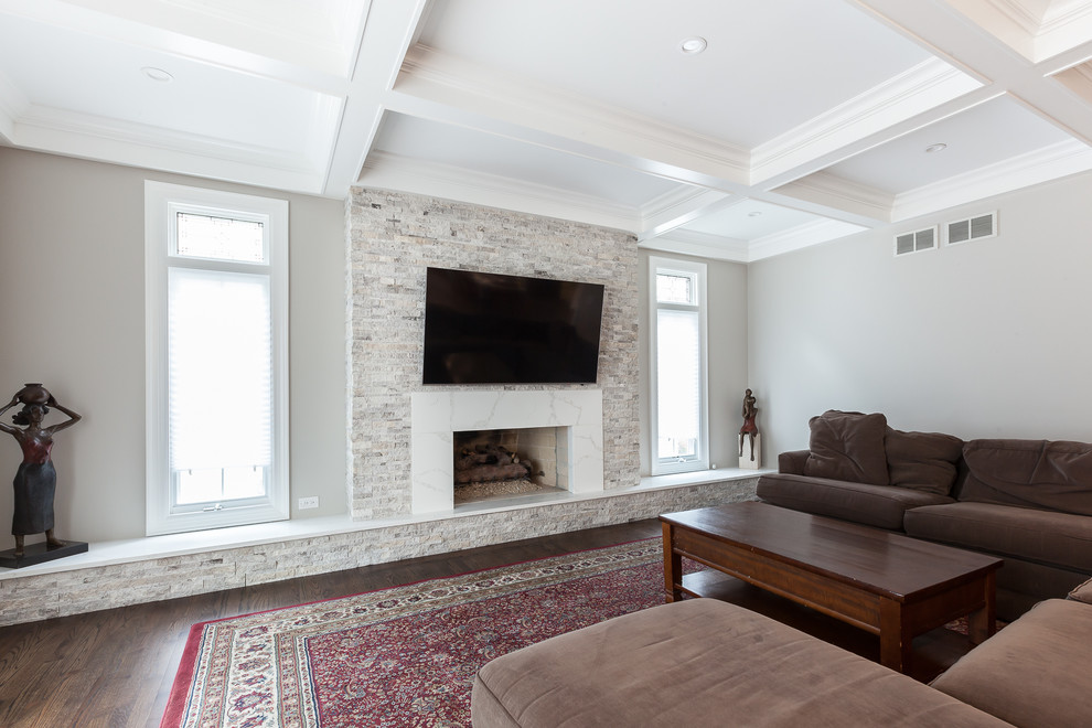 Идея дизайна: открытая гостиная комната в стиле кантри с серыми стенами, паркетным полом среднего тона, стандартным камином, фасадом камина из камня, телевизором на стене и коричневым полом
