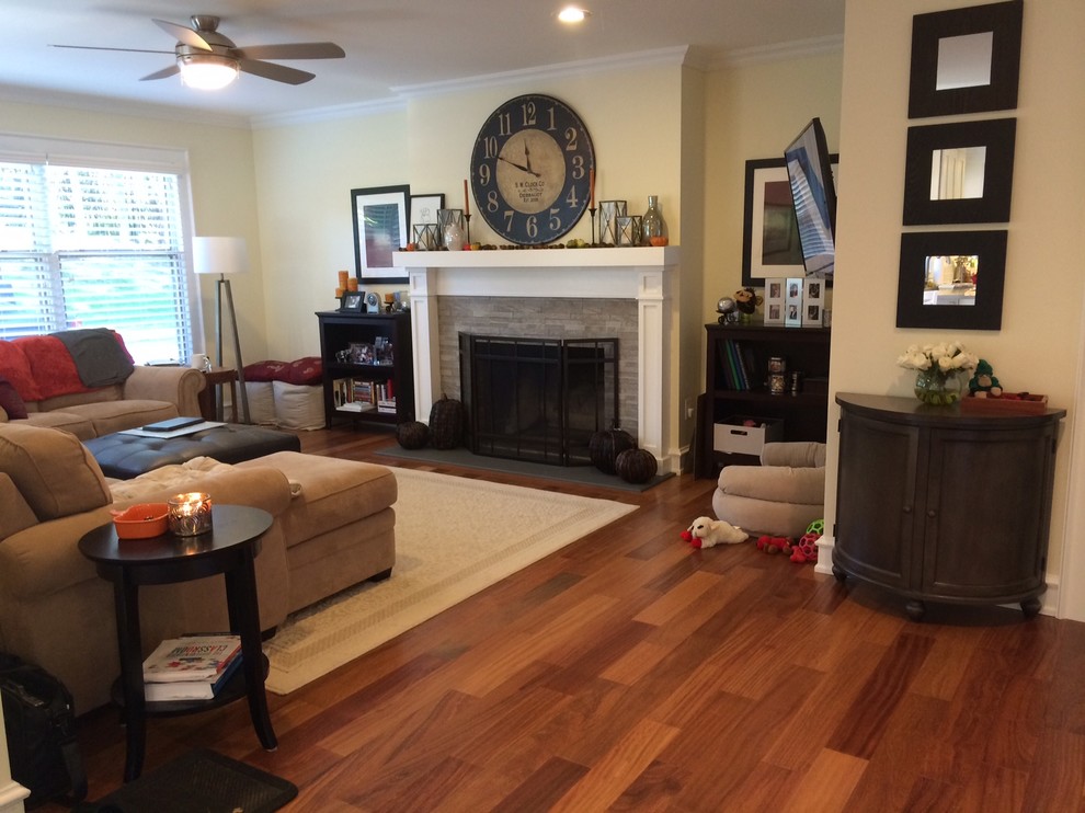 Foto de sala de estar abierta tradicional renovada de tamaño medio con paredes amarillas, suelo de madera en tonos medios, todas las chimeneas, marco de chimenea de piedra y televisor colgado en la pared
