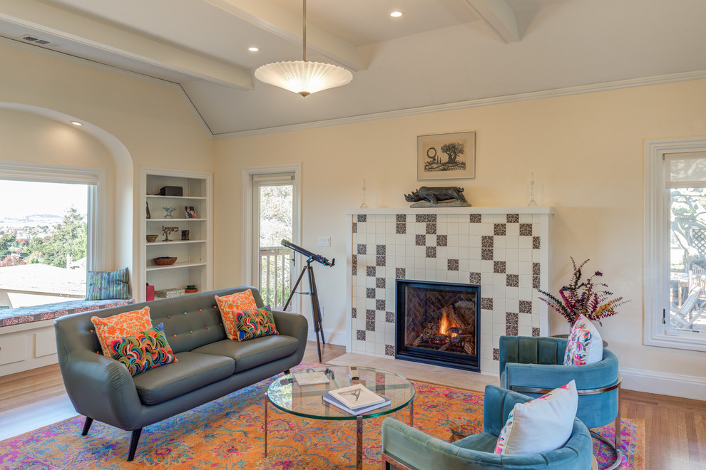 Example of a transitional medium tone wood floor and brown floor family room design in San Francisco with beige walls, a standard fireplace and a tile fireplace