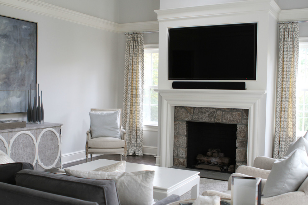 This is an example of a medium sized classic open plan games room in New York with grey walls, dark hardwood flooring, a standard fireplace, a wooden fireplace surround and a wall mounted tv.