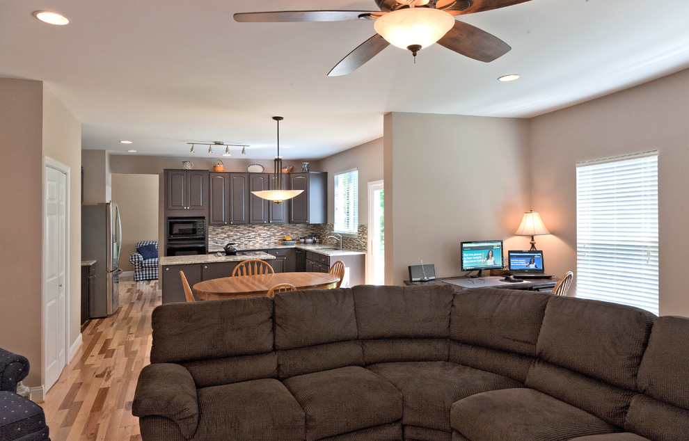 Imagen de sala de estar abierta tradicional de tamaño medio con paredes marrones y suelo de madera clara