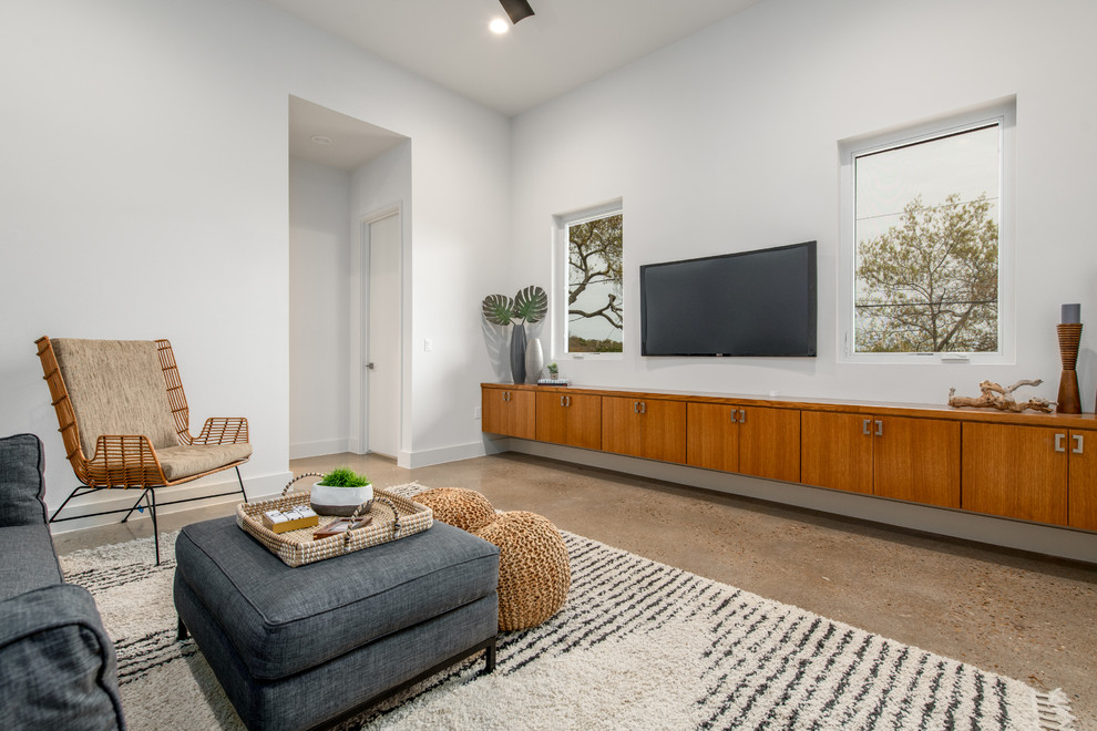 Example of a mid-sized 1950s enclosed concrete floor and beige floor family room design in Austin with white walls, no fireplace and a wall-mounted tv