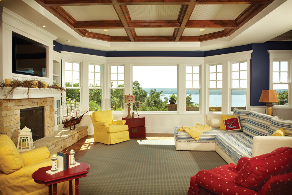 На фото: большая открытая гостиная комната в морском стиле с синими стенами, паркетным полом среднего тона, стандартным камином, фасадом камина из камня, телевизором на стене и коричневым полом с