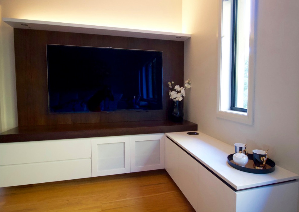 Imagen de sala de estar contemporánea de tamaño medio con paredes grises, suelo de madera en tonos medios, pared multimedia y suelo marrón