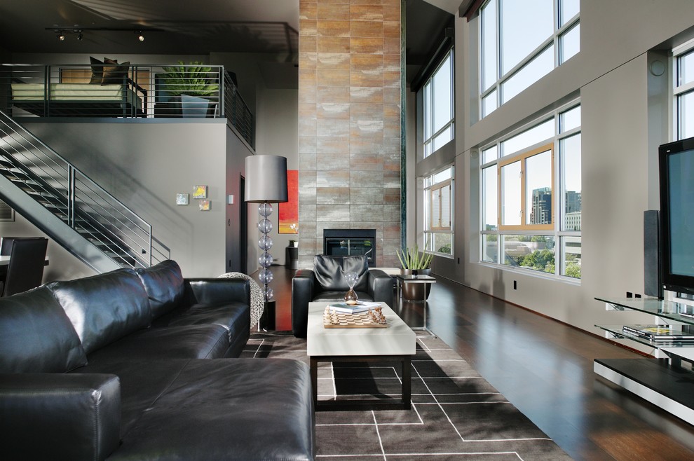Aménagement d'une salle de séjour contemporaine ouverte avec un mur gris, parquet foncé, une cheminée standard, un téléviseur indépendant et canapé noir.