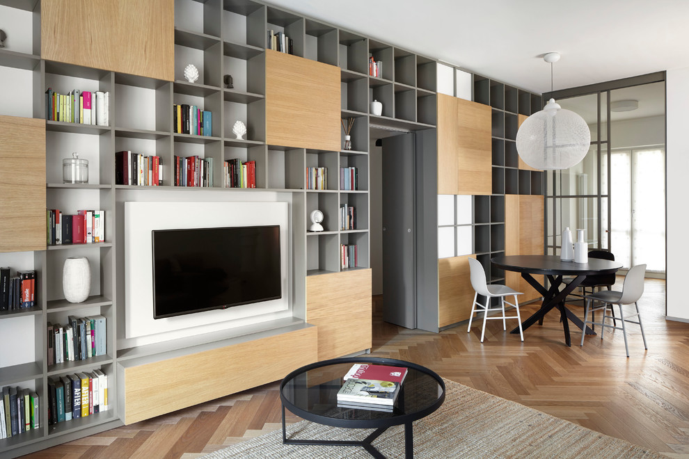 Imagen de sala de estar contemporánea sin chimenea con paredes blancas, suelo de madera en tonos medios y televisor colgado en la pared