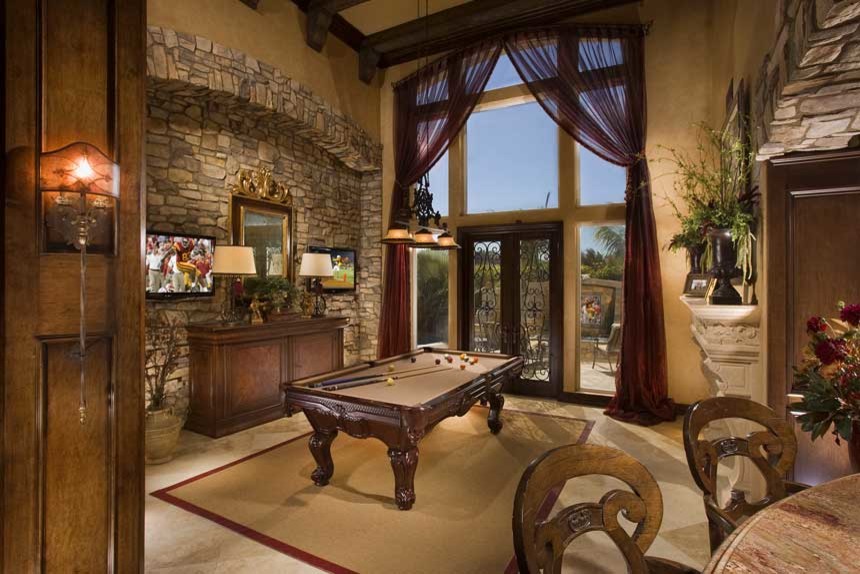 This is an example of a medium sized mediterranean open plan games room in San Diego with a game room, beige walls, porcelain flooring, a standard fireplace, a plastered fireplace surround, no tv and beige floors.