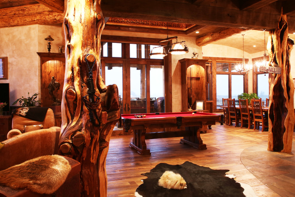 This is an example of a large rustic open plan games room in Albuquerque with a game room, beige walls, medium hardwood flooring, a standard fireplace and a stone fireplace surround.