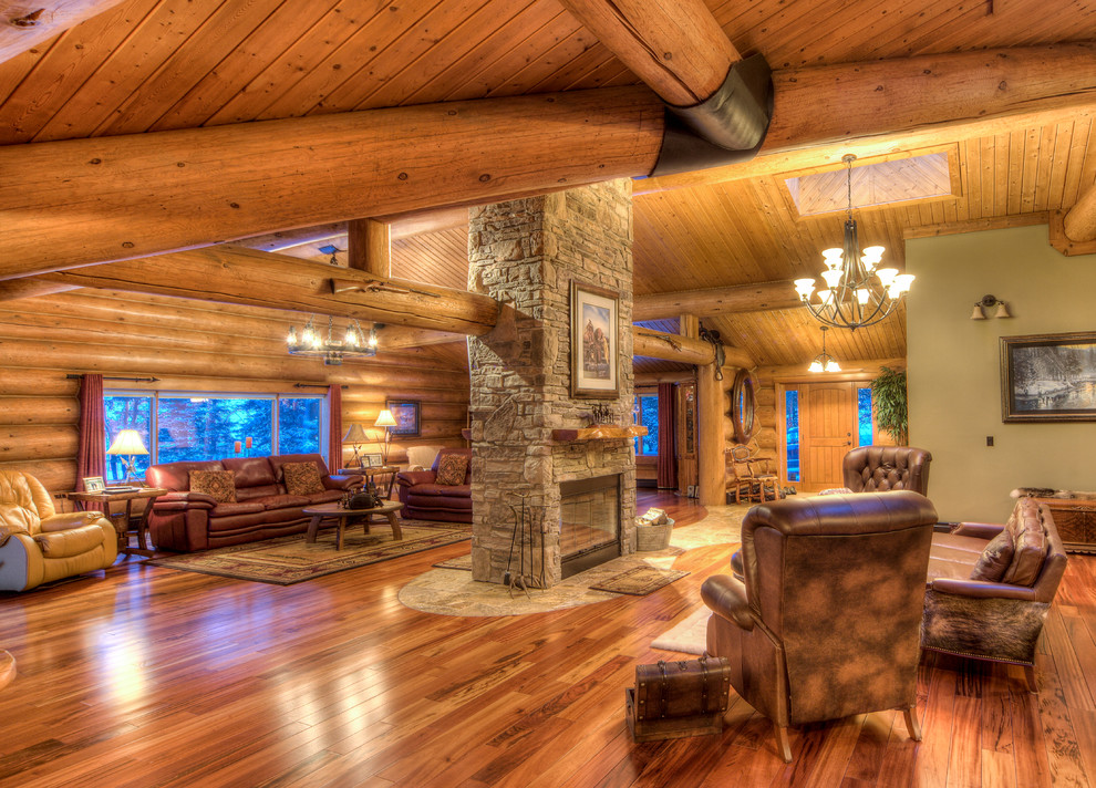 Geräumiges, Fernseherloses Landhausstil Wohnzimmer im Loft-Stil mit beiger Wandfarbe, braunem Holzboden, Tunnelkamin und Kaminumrandung aus Stein in Calgary