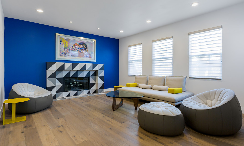 Mittelgroßes, Offenes Modernes Wohnzimmer mit hellem Holzboden, Kamin, gefliester Kaminumrandung, Multimediawand und bunten Wänden in Orange County