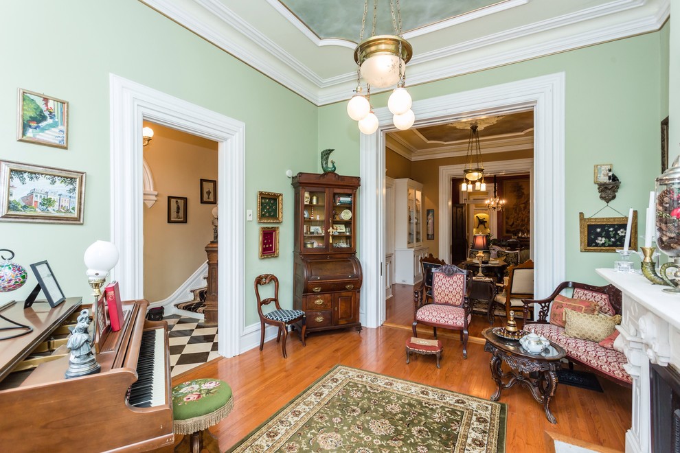Photo of a medium sized victorian enclosed games room in St Louis with a music area, green walls, light hardwood flooring, a standard fireplace and no tv.