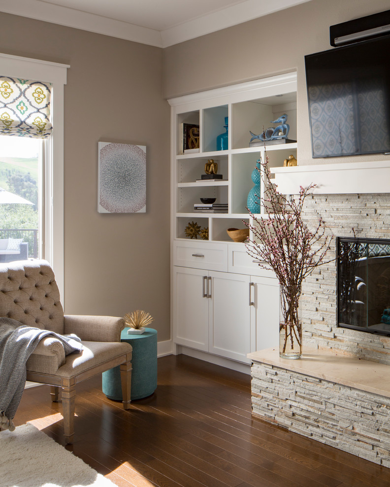 Cette photo montre une salle de séjour chic de taille moyenne et ouverte avec un mur beige, parquet foncé, une cheminée standard, un manteau de cheminée en pierre, un téléviseur fixé au mur et un sol marron.