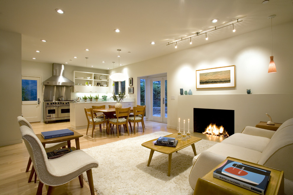 Imagen de sala de estar abierta vintage grande con paredes blancas, suelo de madera clara, todas las chimeneas y marco de chimenea de yeso