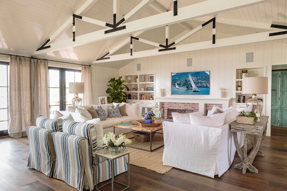 Maritimes Wohnzimmer mit weißer Wandfarbe, Kamin, Kaminumrandung aus Backstein, TV-Wand, braunem Boden und braunem Holzboden in Orange County