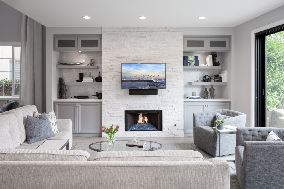 Ejemplo de sala de estar abierta clásica renovada con paredes grises, todas las chimeneas, piedra de revestimiento, televisor colgado en la pared y suelo gris