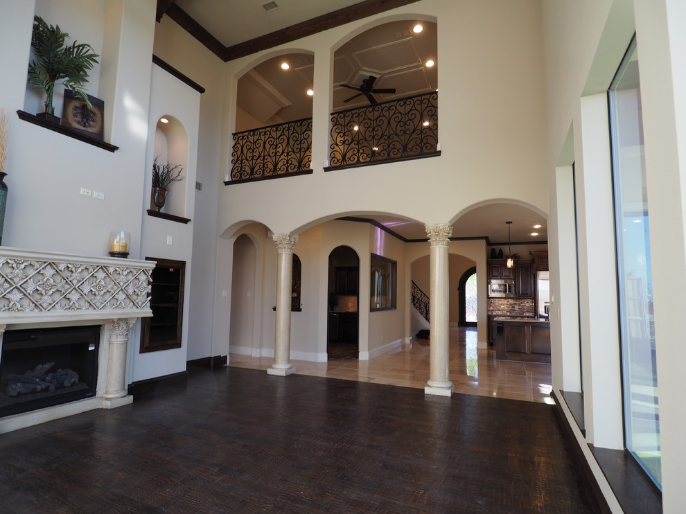 Photo of a large mediterranean enclosed games room in Dallas with beige walls, dark hardwood flooring, a standard fireplace, a plastered fireplace surround and no tv.