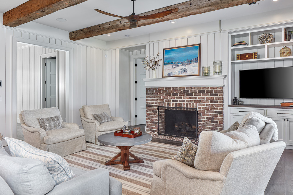 Inspiration pour un salon marin fermé avec un mur blanc, un sol en bois brun, une cheminée standard, un manteau de cheminée en brique et un téléviseur encastré.